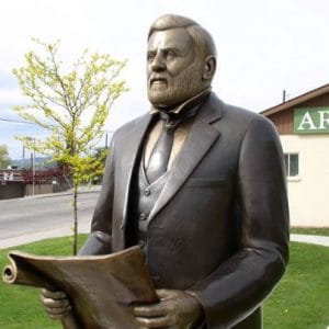 Metal statue of bearded man in suit, holding a piece of parchment